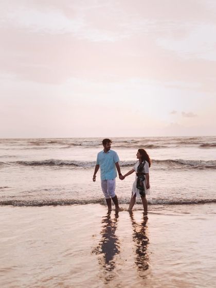 A quiet walk along the shoreline, hand in hand. The soft light and their reflection in the water create a peaceful and romantic atmosphere.