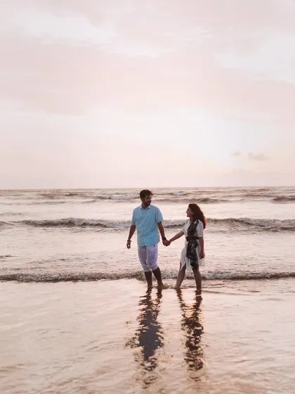 A quiet walk along the shoreline, hand in hand. The soft light and their reflection in the water create a peaceful and romantic atmosphere.
