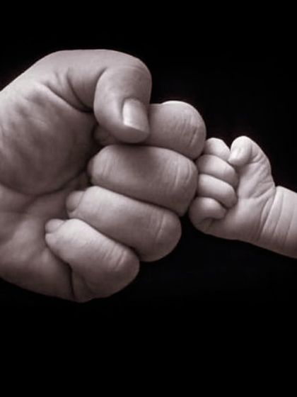 A symbolic fist bump between parent and child. This iconic shot represents the instant, powerful bond and is a client favorite for its simple yet profound message.