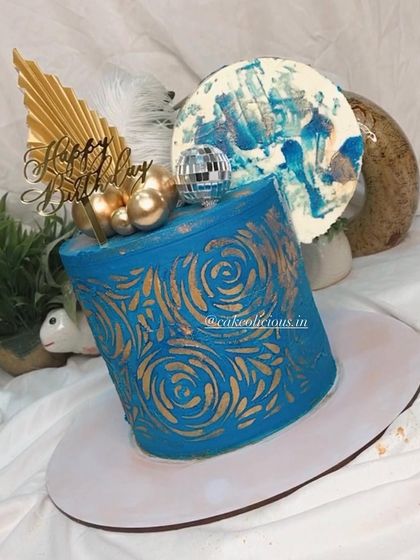 An asymmetrical cake I made for my brother's birthday. This modern design features a bold blue ganache with a gold stenciled pattern, topped with a disco ball, feathers, and an abstract chocolate sail.