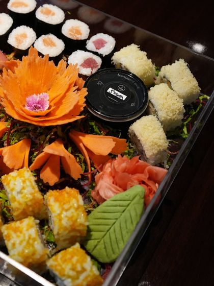 This platter highlights a mix of crunchy tempura rolls and classic maki, garnished with a carved vegetable flower. It's a perfect balance of textures and flavors for any party.