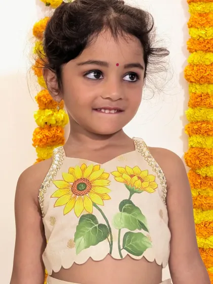 A closer look at the artistry of our signature hand-painted blouses. This piece features a vibrant sunflower, with each brushstroke carefully applied by our artisans to create a truly one-of-a-kind garment for your child.
