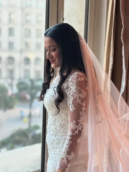 A close-up of the bride by the window, her soft curls and natural makeup creating a timeless and elegant look.