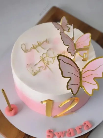 A sweet and simple 12th birthday cake with a pink ombre design and elegant gold-accented butterflies.
