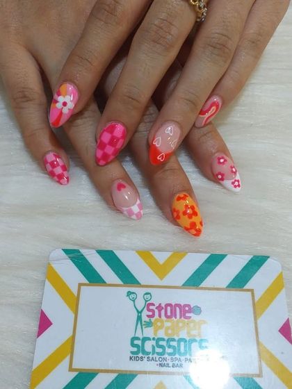 A playful and colorful set that combines multiple trends. I used a pink checkerboard pattern, floral details, and heart cutouts for a fun, mismatched look on stiletto nails.