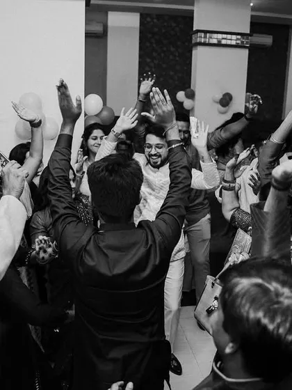The dance floor is where the energy is. A wide, black and white shot of the Sangeet party in full swing, capturing the collective joy of friends and family.