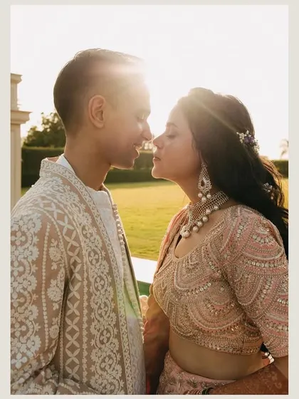 A sun-kissed moment of affection. The lens flare adds a dreamy, romantic quality to this close-up of the couple, capturing their love and the beautiful light of their Mehendi day.