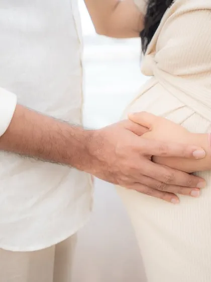 Sometimes the simplest gestures tell the biggest story. This close-up shot focuses on the couple's hands gently cradling the baby bump, a powerful and intimate detail from their outdoor pregnancy photoshoot.