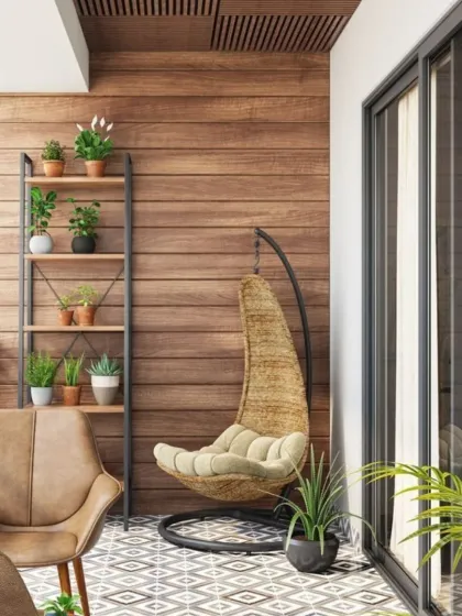 This balcony combines different seating styles with a wicker swing chair and a leather armchair for a relaxed, eclectic vibe. The wood-paneled wall and patterned floor tiles add warmth and character, while a ladder shelf provides vertical storage for plants.