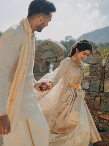 A candid moment of the couple walking hand-in-hand at their destination wedding, dressed in elegant South Indian attire.