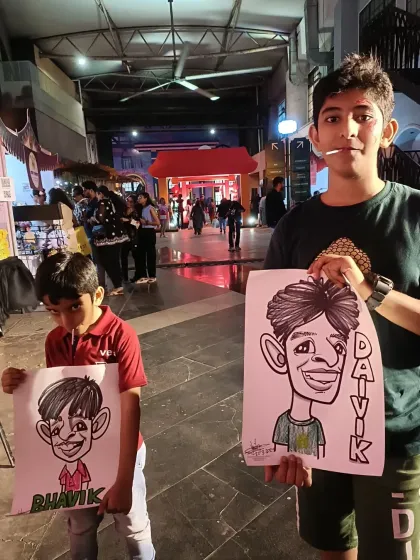 Two brothers with their individual caricatures at a lively night market event.
