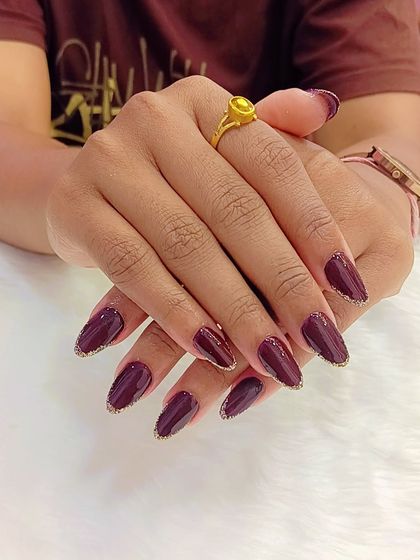 A little wine, a lot of glam. These deep wine-colored nails are given a touch of sparkle with a delicate gold glitter outline at the tips.