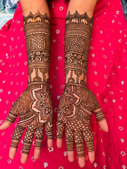 This design features a floral mandala on the palm and architectural-inspired patterns on the forearm. A band of elephants at the top adds a traditional touch.