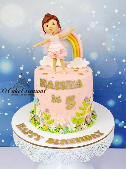 A sweet single-tier cake for Kaisha's 5th birthday, featuring a ballerina fairy, a rainbow, and a field of delicate buttercream flowers.