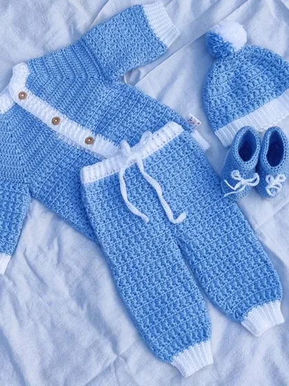 A complete newborn baby winter set in soft blue and white yarn. The set includes a cozy cardigan, pants with a drawstring, a pom-pom hat, and adorable little booties.