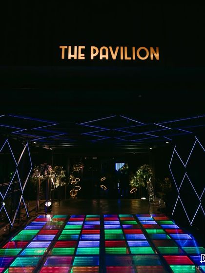 The entrance to "The Pavilion" for the Sangeet night in Goa, featuring a vibrant, multi-colored LED dance floor and a geometric light tunnel.