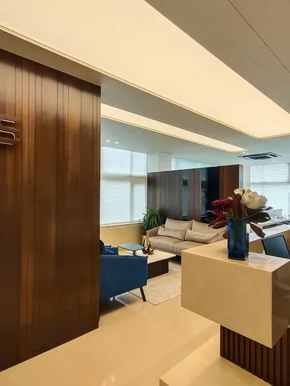 The reception and waiting area of the RS head office in Chennai. I used warm wood paneling, a minimalist reception desk, and soft, integrated ceiling lights to establish a professional and welcoming atmosphere for a leading corporate headquarters.
