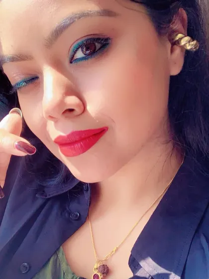 A close-up selfie from a vacation, featuring a pop of blue eyeliner and a bold red lip.