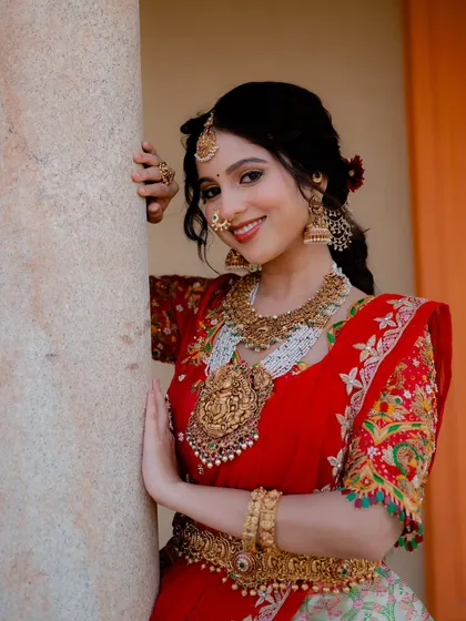 A close-up portrait of actress Niveditha Gowda, showcasing her stunning bridal jewelry and makeup. The soft lighting and her gentle smile create a classic and elegant bridal look.