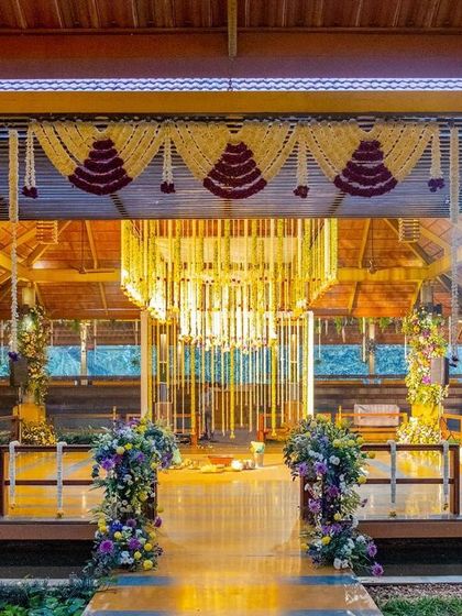The entrance to the traditional Muhurtham, framed by floral pillars and leading towards the stunning chandelier mandap.