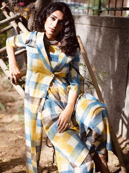 A more stylized, seated pose that gives the plaid outfit an editorial feel. This kind of shot adds variety to a brand's social media feed or lookbook, showing the garment's potential for more fashion-forward styling.