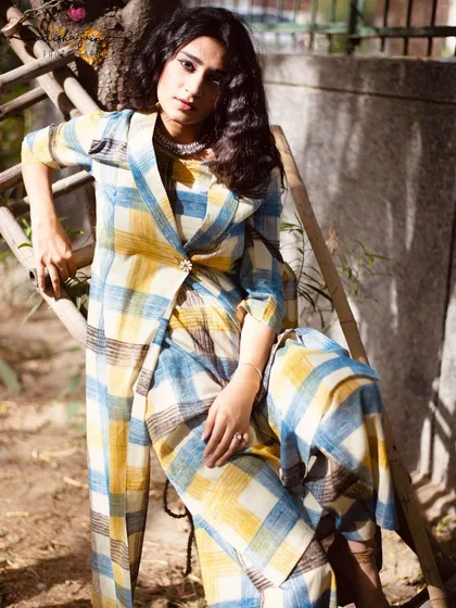 A more stylized, seated pose that gives the plaid outfit an editorial feel. This kind of shot adds variety to a brand's social media feed or lookbook, showing the garment's potential for more fashion-forward styling.