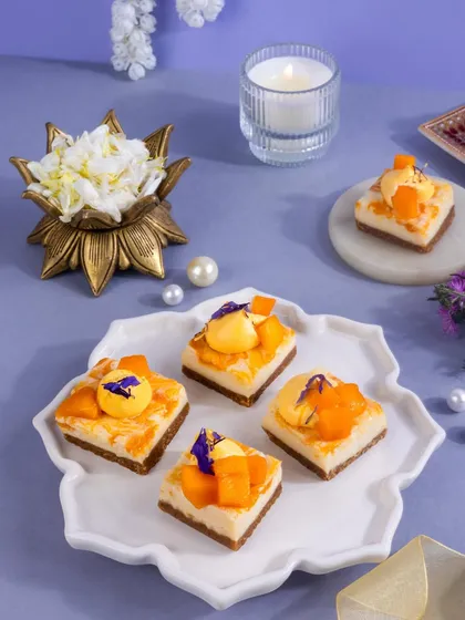 These mango and coconut mini cakes are a tropical delight. The styling with fresh flowers and pearls on a decorative plate gives them a luxurious and celebratory feel.