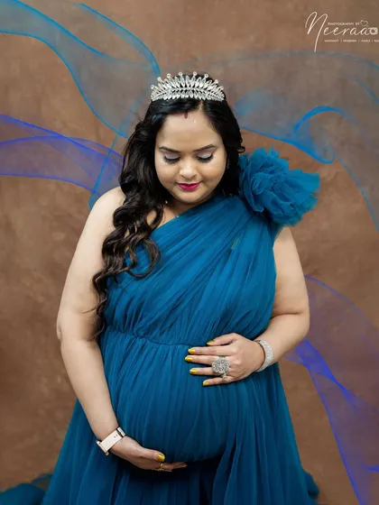 Looking down at her precious bump. With a tiara on her head, this portrait is a sweet and regal moment of connection between mother and child.