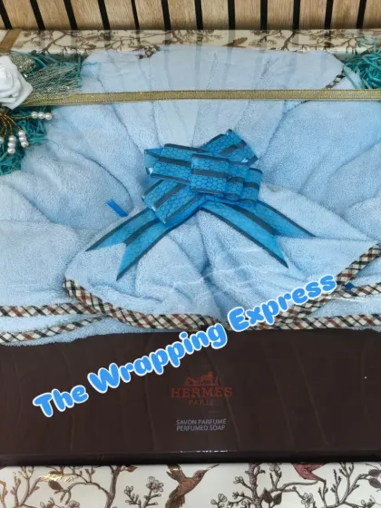 A neatly packed trousseau gift containing a bathrobe and Hermes perfumed soap, decorated with a blue bow.