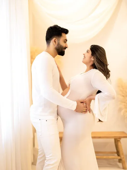 A joyful, interactive pose from the all-white session. Capturing genuine smiles and laughter is a key part of my process for couple maternity photography.