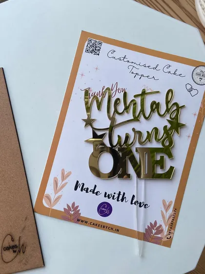 The "Mehtab turns ONE" topper, shown here in its packaging, highlighting the "Made with love" message I include with every order.
