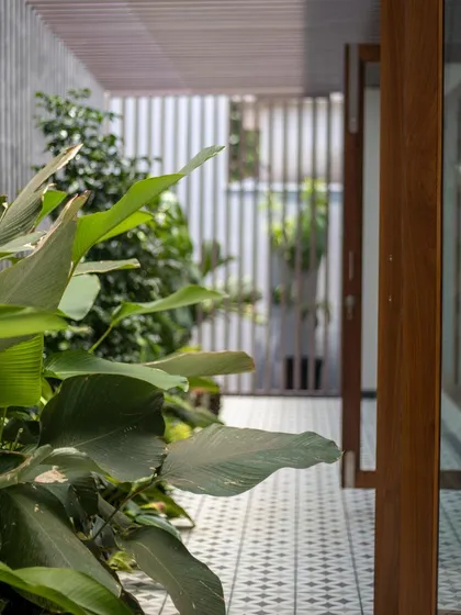 This corridor showcases the interplay of indoor and outdoor living. The patterned tile flooring leads the eye through the space, flanked by lush greenery that brings the calming influence of nature right into the home.