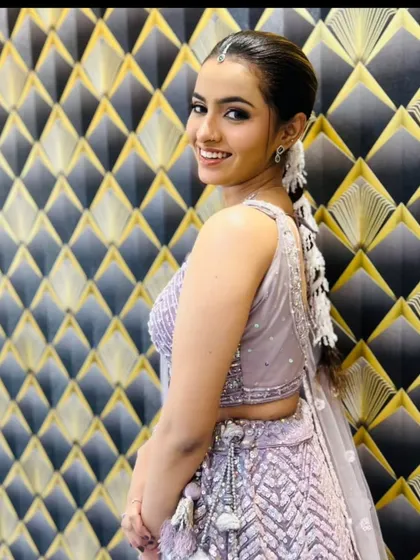 A smiling client posing against a stylish backdrop in the lavender lehenga.