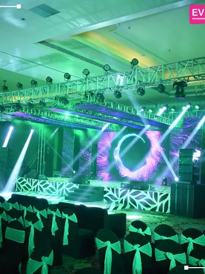 The same Sangeet stage seen with dynamic green lighting, showcasing the versatility of the setup to change the mood and energy of the room.