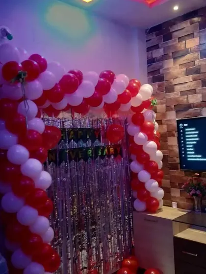 Even a small space at home can be transformed for a special anniversary. Here, I created a red and white balloon arch over the entertainment unit, using a silver shimmery curtain as a backdrop to add a touch of glamour.