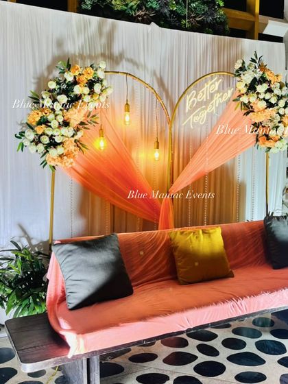 A heart-shaped arch with peach and white florals, a 'Better Together' neon sign, and a comfortable swing for a romantic outdoor engagement.