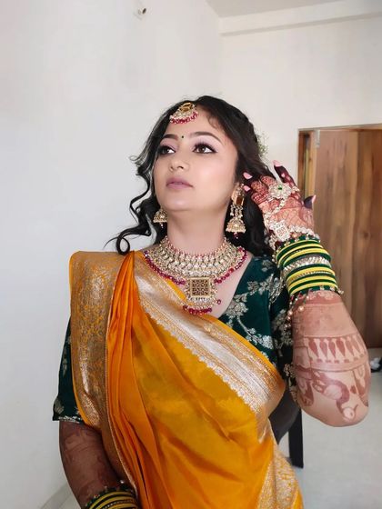 The bride is adjusting her earring, giving a nice view of the side profile and the complete look with jewellery.