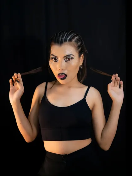 A catwalk makeup look with bold graphic eyeliner, a black lip, and glitter accents.