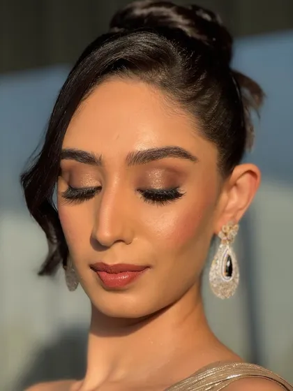 A close-up with eyes closed, showing the artistry of the eyeshadow blending. The warm brown and gold tones create a classic smokey eye that is perfect for any glamorous occasion.