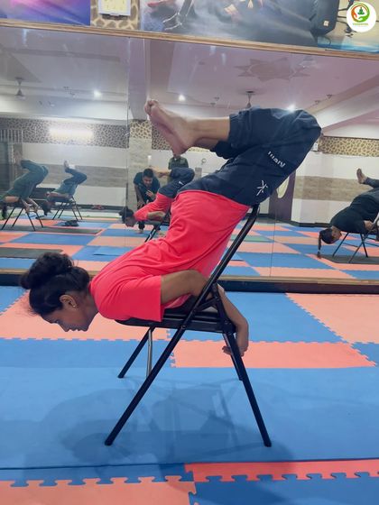 The reflection in the mirror shows the alignment and form during a chair-supported backbend. We focus on safe and effective practice for every student.