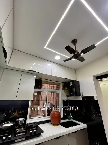 This kitchen features a stunning black patterned backsplash that contrasts beautifully with the white countertops and cabinets. The profile lighting in the ceiling provides excellent, even illumination.