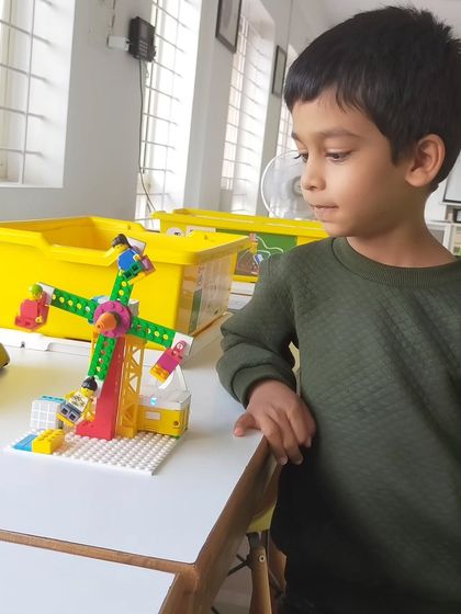 The pride of creation is a powerful motivator. A young student proudly stands by the Ferris wheel he built, a project that combines mechanical design with programming.
