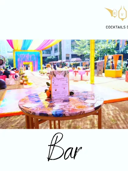 A colorful bar setup for a daytime Mehendi function. The bright decor and custom tabletop create a festive and welcoming spot for guests to grab a refreshing drink.