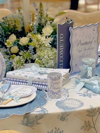 A detailed look at a table centerpiece for the carnival party. The custom-printed tablecloth, personalized signage, and fresh floral arrangements create a cohesive and luxurious guest experience.