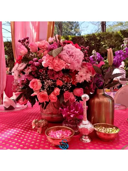 Another view of the pink-themed tablescape, highlighting the lush floral arrangement in metallic vases. We use color and texture to create a rich, celebratory feel for daytime events.