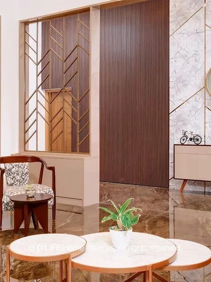 This living room features elegant printed armchairs, marble-topped nesting tables, and a striking wall with geometric gold inlay, creating a sophisticated and artistic space.