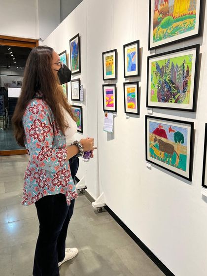 An attendee looking closely at the vibrant artworks created by our students.