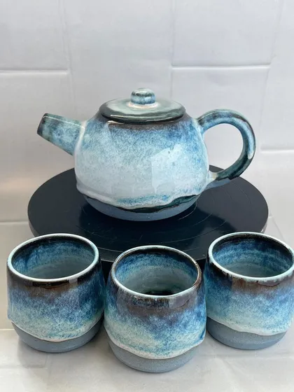 A complete handmade teapot set, finished in a beautiful, flowing blue glaze that reminds me of the sea. This set includes a wheel-thrown teapot with a comfortable handle and three matching cups, perfect for sharing a quiet moment.