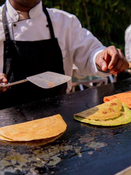 A chef in action, expertly preparing colorful moong dal chillas on a hot griddle. This live cooking element adds a dynamic and engaging touch to the event.