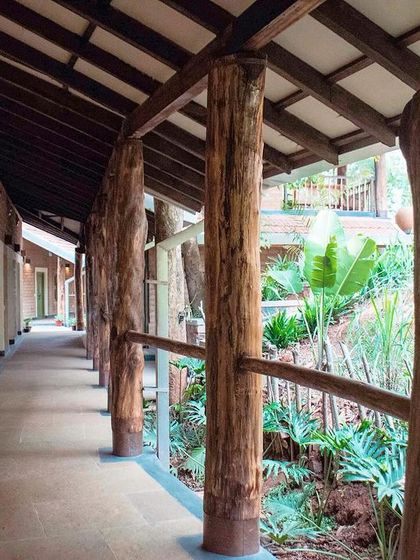 The long, open corridor of the residential block at PLENTI House, supported by locally sourced eucalyptus logs.